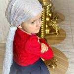 Дитина у святковому вбранні поруч із золотими церемоніальними свічниками — момент традиції та щирості Анечки Захарової